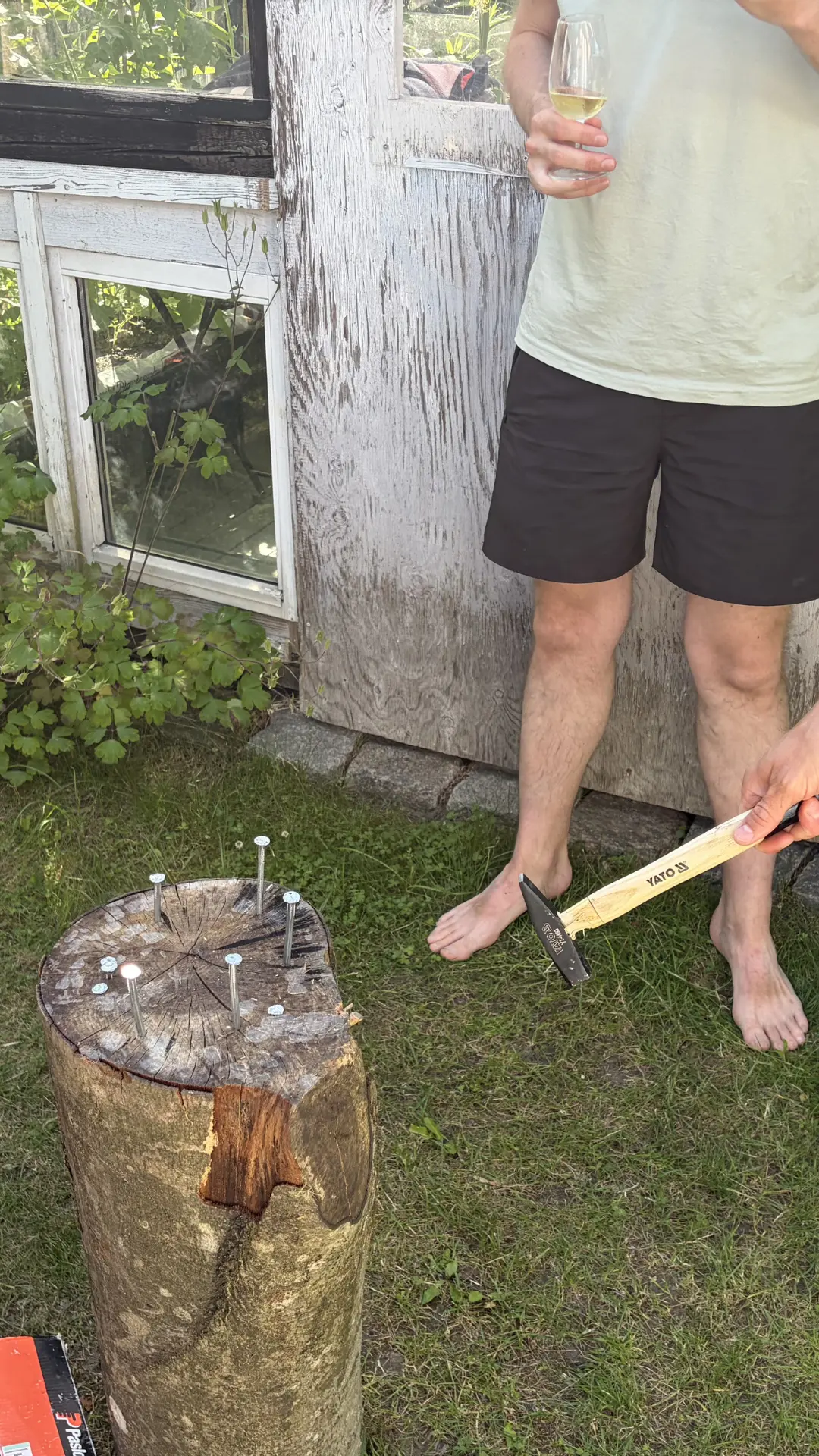 Sømblok med søm og hammer i hånden ved sommerhus